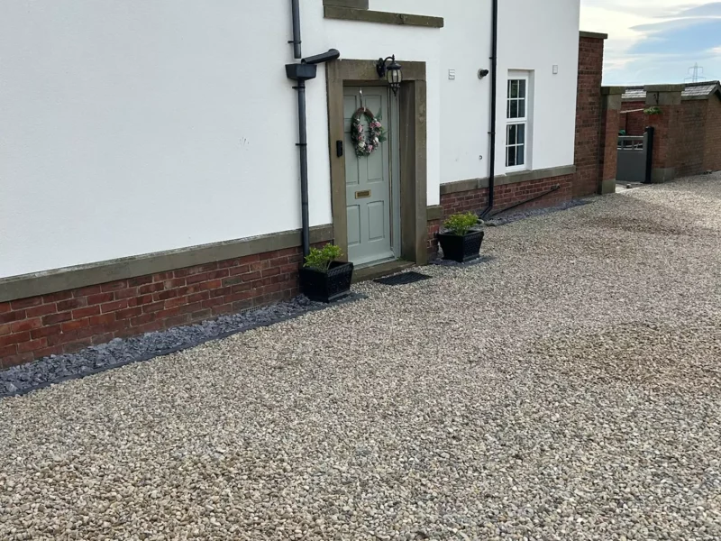 Gravel driveway in front of white house