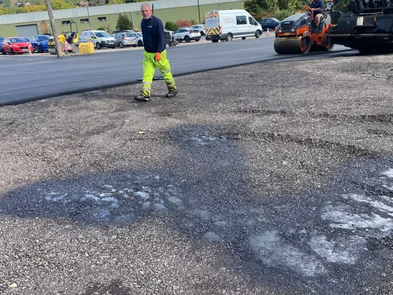 A roller compacting fresh tarmac for a new car park surface