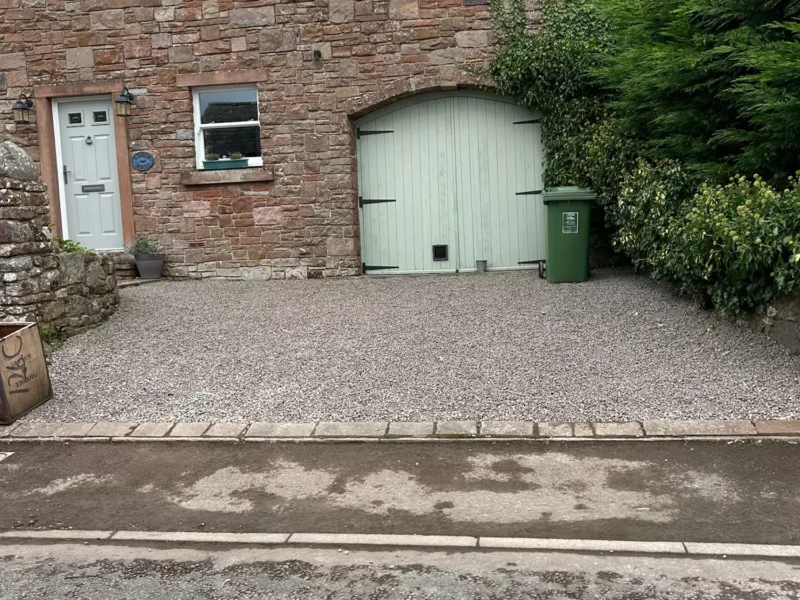 Gravel driveway in front of a stone residential home