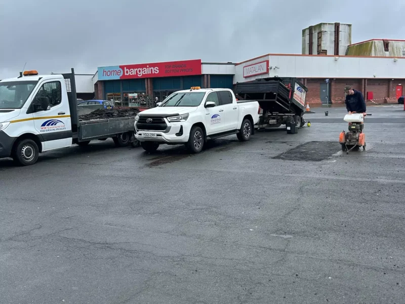 Pothole in front of Home Bargins being fixed by a member of the team