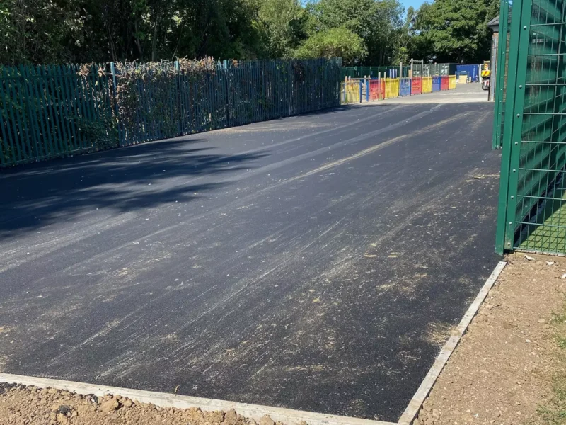 A new large tarmac area in front of a green metal fence