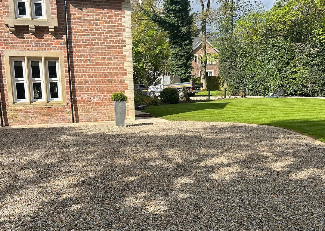 Gravel drive next to a brick house with a WW Contracts van in the background