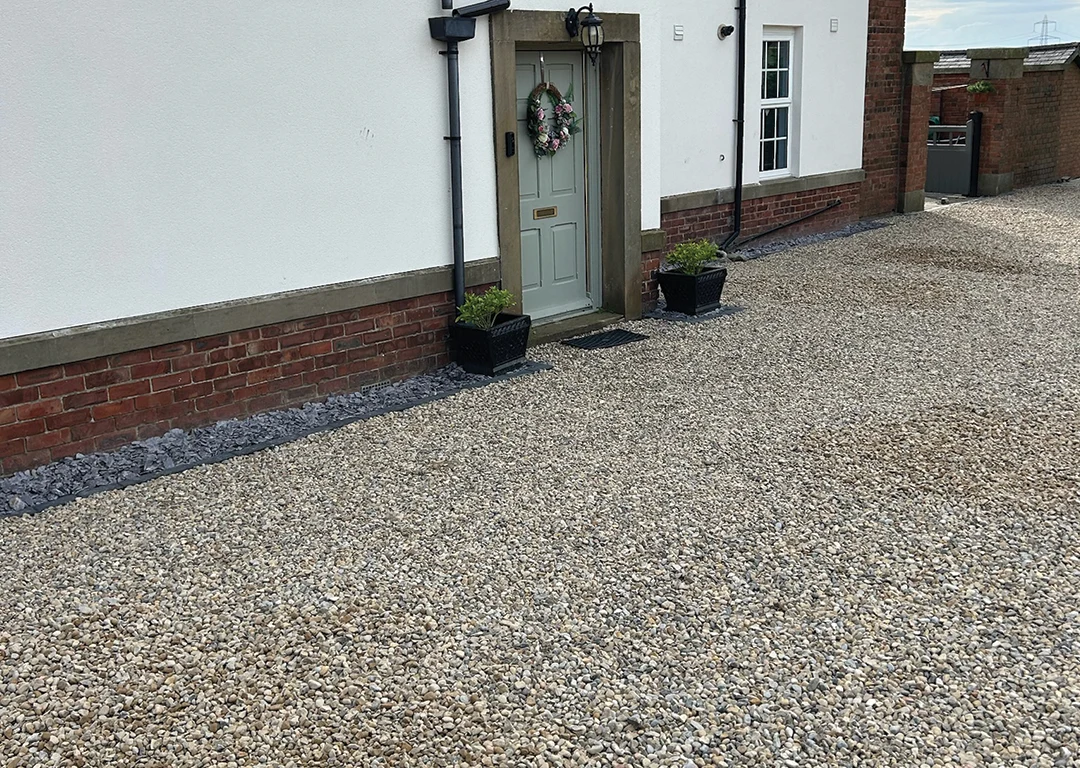 Gravel driveway in front of white house