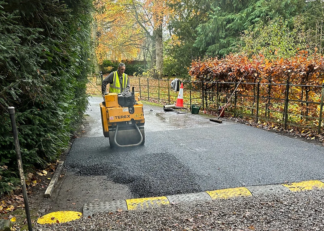Road resurfacing in progress with man on roller