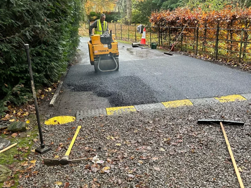 Steamroller compacting fresh tarmac on a short stretch of road.