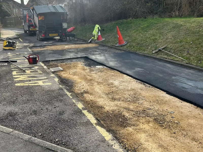 Road repair in progress with fresh tarmac being laid