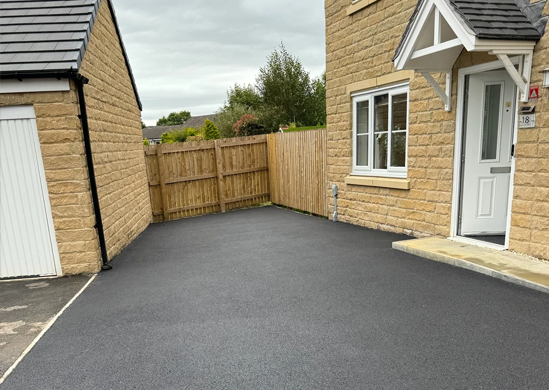 A freshly installed tarmac drive next to a new build home